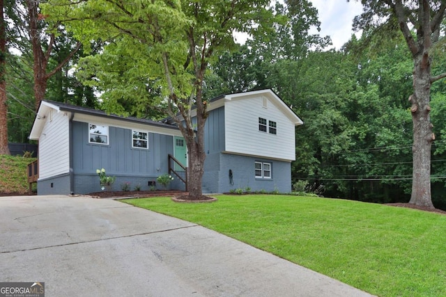 split level home featuring brick siding, board and batten siding, and a front yard