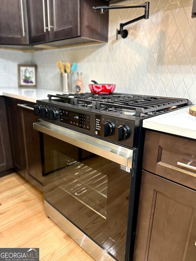 kitchen featuring tasteful backsplash, dark brown cabinets, and range with gas cooktop