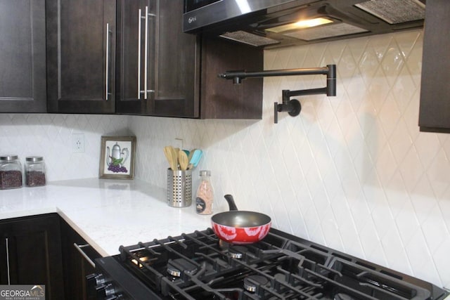 kitchen featuring light stone counters, tasteful backsplash, extractor fan, and dark brown cabinetry