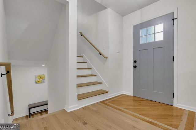 foyer entrance featuring stairs, baseboards, and wood finished floors