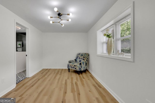 unfurnished room with a chandelier, wood finished floors, and baseboards