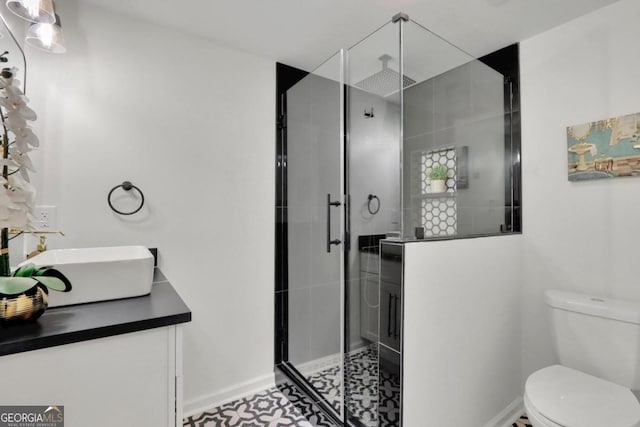 bathroom featuring vanity, a shower stall, toilet, and baseboards