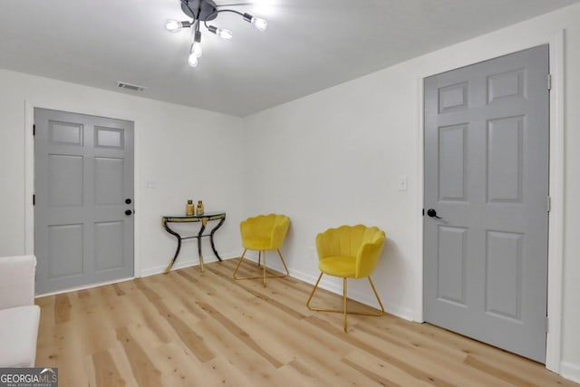 sitting room with baseboards, visible vents, and wood finished floors