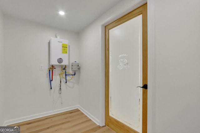 washroom with baseboards, recessed lighting, tankless water heater, and light wood-style floors