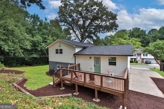 back of house with roof with shingles, a yard, a wooden deck, and central AC unit