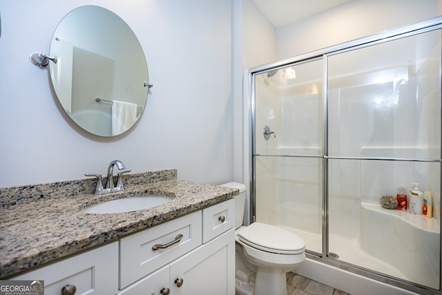 bathroom with vanity, a shower with shower door, and toilet