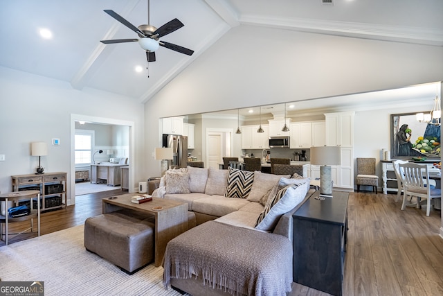 living room with beamed ceiling, ceiling fan with notable chandelier, hardwood / wood-style flooring, and high vaulted ceiling