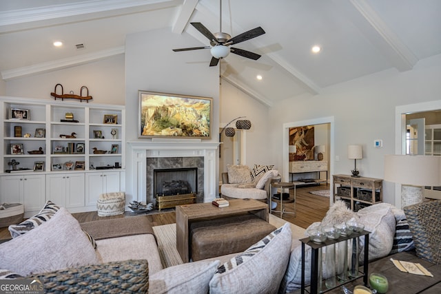 living room with ceiling fan, beamed ceiling, hardwood / wood-style flooring, a fireplace, and ornamental molding