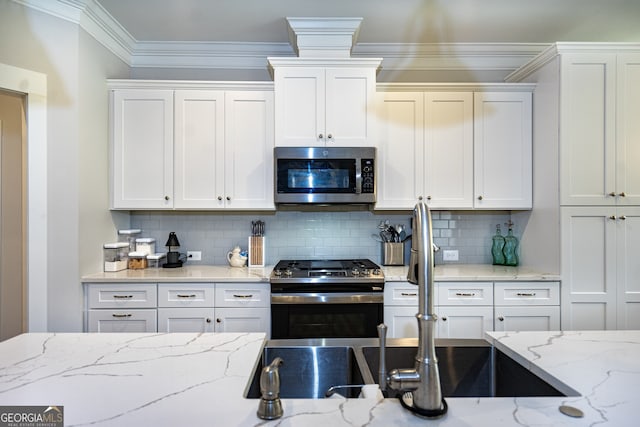 kitchen featuring white cabinets, backsplash, stainless steel appliances, and light stone countertops