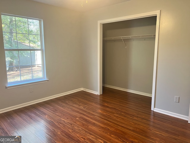 unfurnished bedroom with a closet and dark hardwood / wood-style flooring