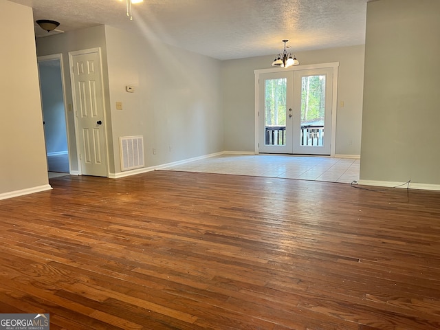 unfurnished room with a textured ceiling, light hardwood / wood-style flooring, and french doors