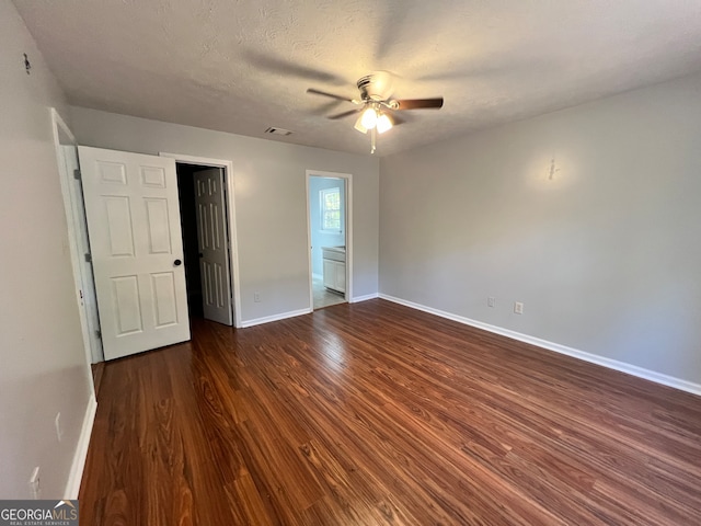 unfurnished bedroom with ceiling fan, a textured ceiling, dark hardwood / wood-style floors, and ensuite bath