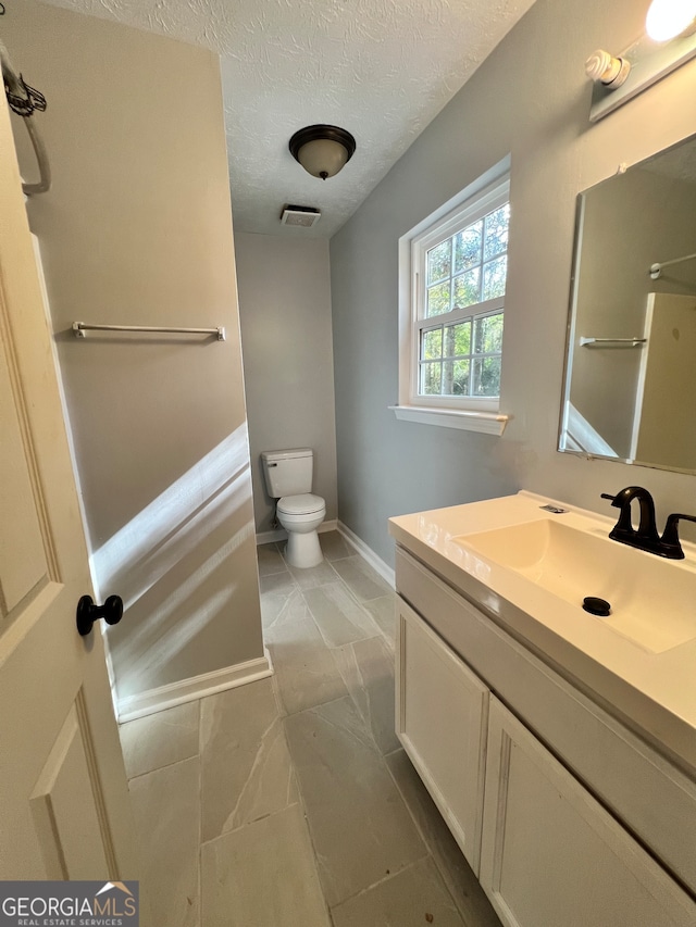 bathroom featuring toilet, vanity, and a textured ceiling