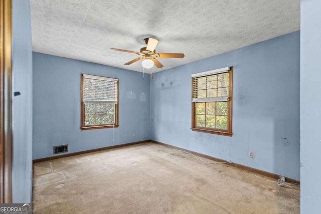 spare room with light colored carpet, a textured ceiling, and ceiling fan