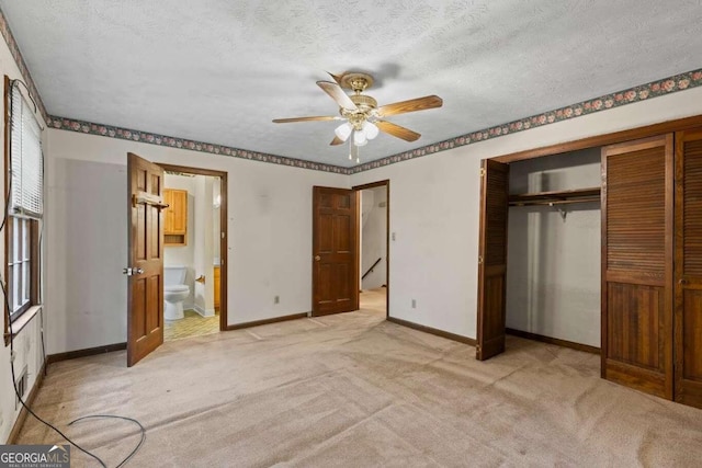 unfurnished bedroom featuring a closet, ensuite bath, a textured ceiling, light carpet, and ceiling fan