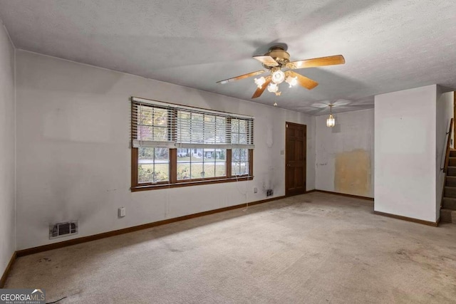 carpeted empty room featuring ceiling fan and a textured ceiling