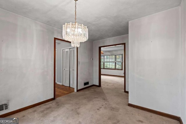 carpeted empty room with a notable chandelier