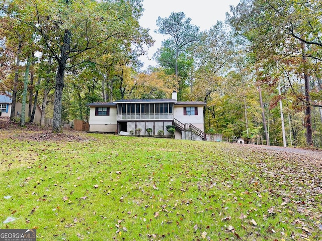 rear view of house with a sunroom and a yard