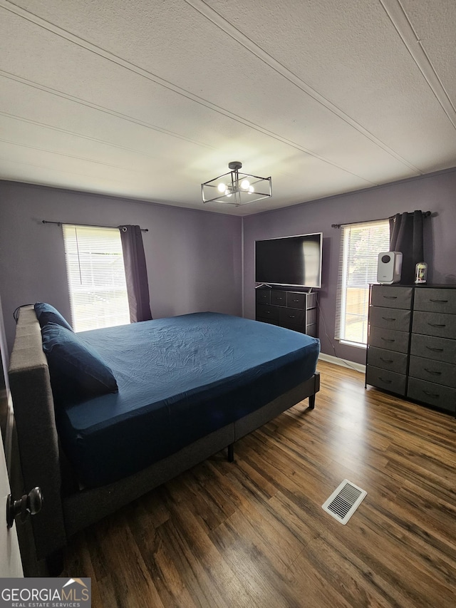 bedroom featuring hardwood / wood-style floors, a notable chandelier, and a textured ceiling