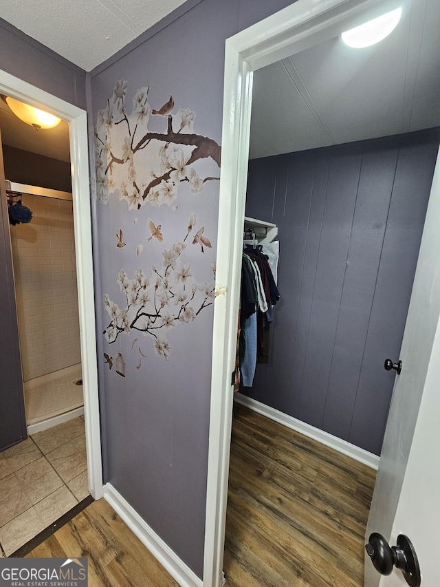 bathroom featuring hardwood / wood-style floors, walk in shower, and wooden walls