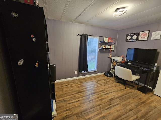 office area with wood walls, a textured ceiling, and hardwood / wood-style flooring