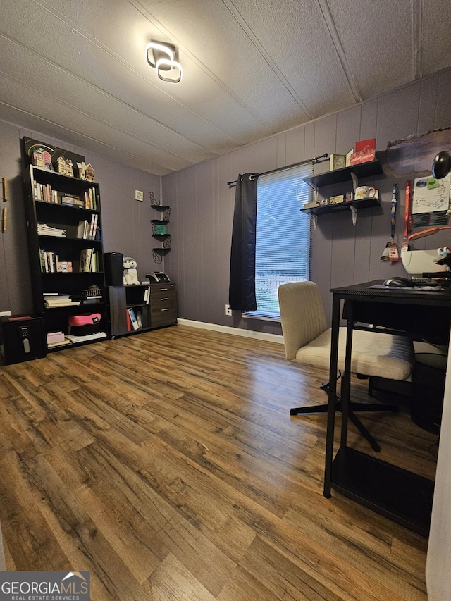 office space with a textured ceiling, hardwood / wood-style flooring, and wood walls