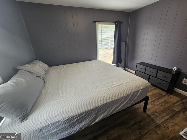 bedroom with wooden walls and dark wood-type flooring