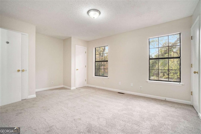 spare room featuring a textured ceiling and light carpet