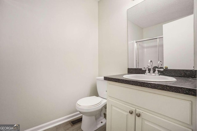 bathroom featuring walk in shower, a textured ceiling, hardwood / wood-style floors, vanity, and toilet