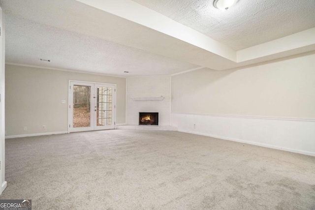 unfurnished living room with a fireplace, a textured ceiling, french doors, and carpet floors