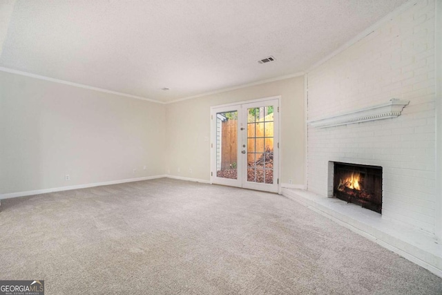 unfurnished living room featuring a brick fireplace, ornamental molding, french doors, and carpet floors