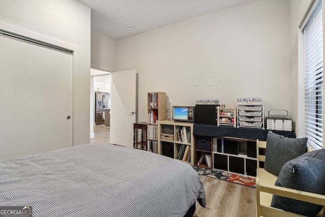 bedroom featuring a closet, stainless steel fridge, and light hardwood / wood-style floors