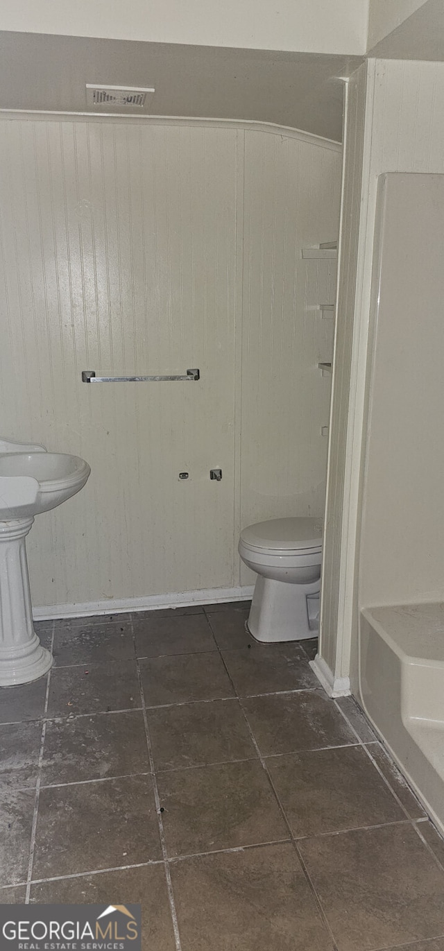 bathroom with a bathing tub, tile patterned flooring, and toilet