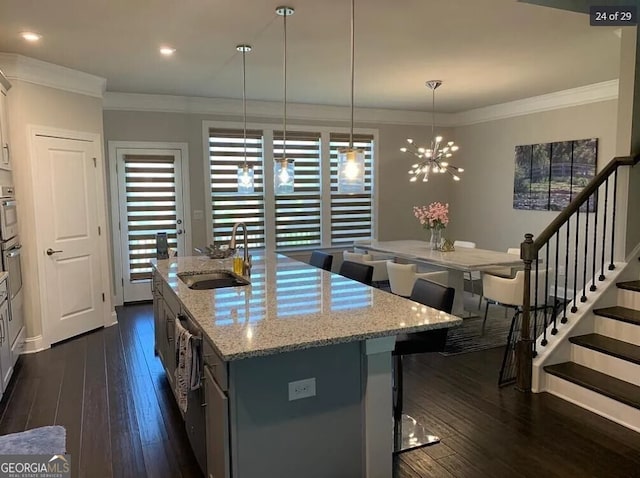 kitchen featuring decorative light fixtures, dark hardwood / wood-style floors, a kitchen island with sink, and sink