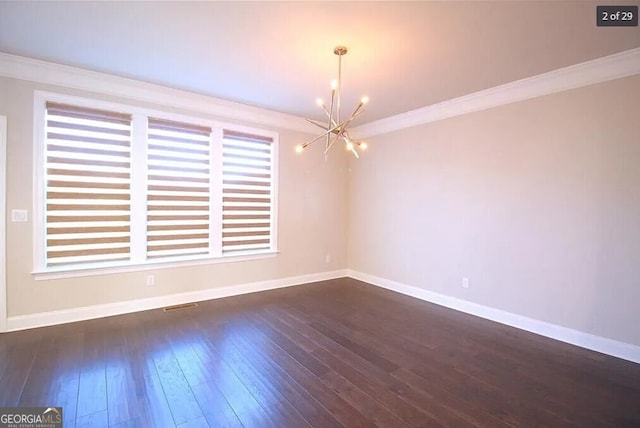 unfurnished room with dark hardwood / wood-style floors, plenty of natural light, crown molding, and an inviting chandelier