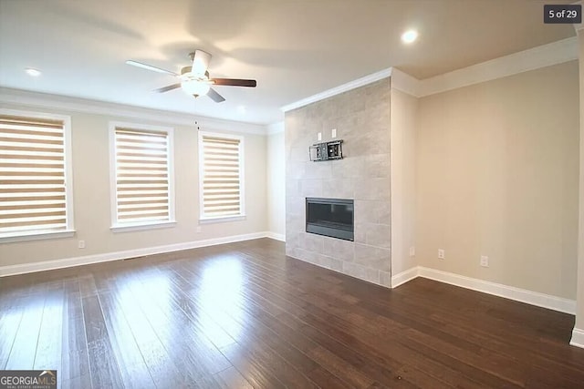 unfurnished living room featuring a fireplace, crown molding, dark hardwood / wood-style flooring, and ceiling fan