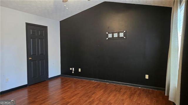 empty room with lofted ceiling, dark hardwood / wood-style floors, and ceiling fan