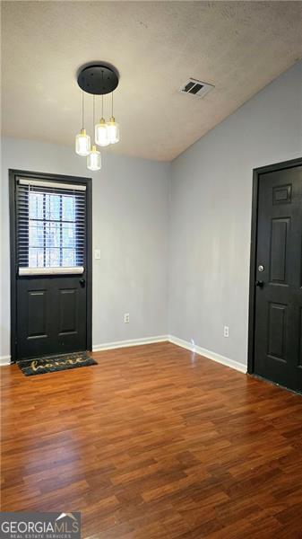 foyer with a textured ceiling, vaulted ceiling, and wood-type flooring