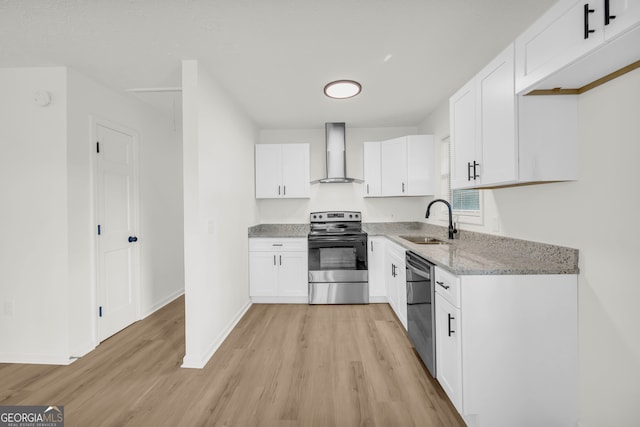 kitchen featuring stainless steel appliances, white cabinetry, wall chimney range hood, sink, and light hardwood / wood-style floors