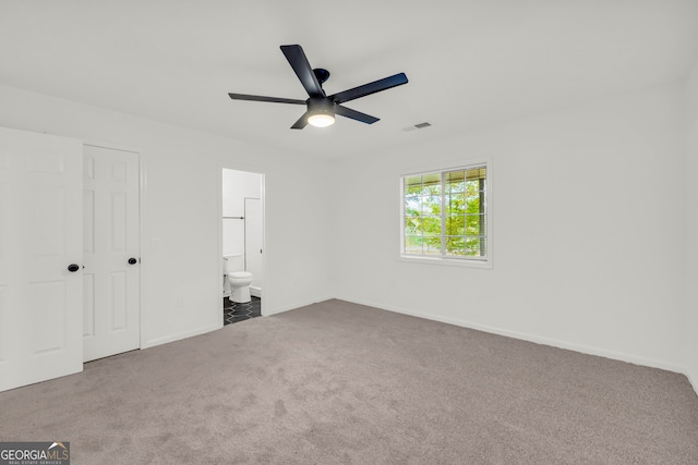 unfurnished bedroom with ceiling fan, ensuite bath, and carpet floors