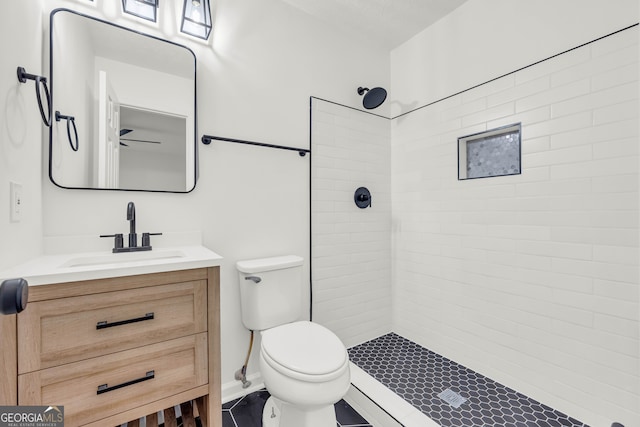 bathroom featuring a tile shower, vanity, and toilet