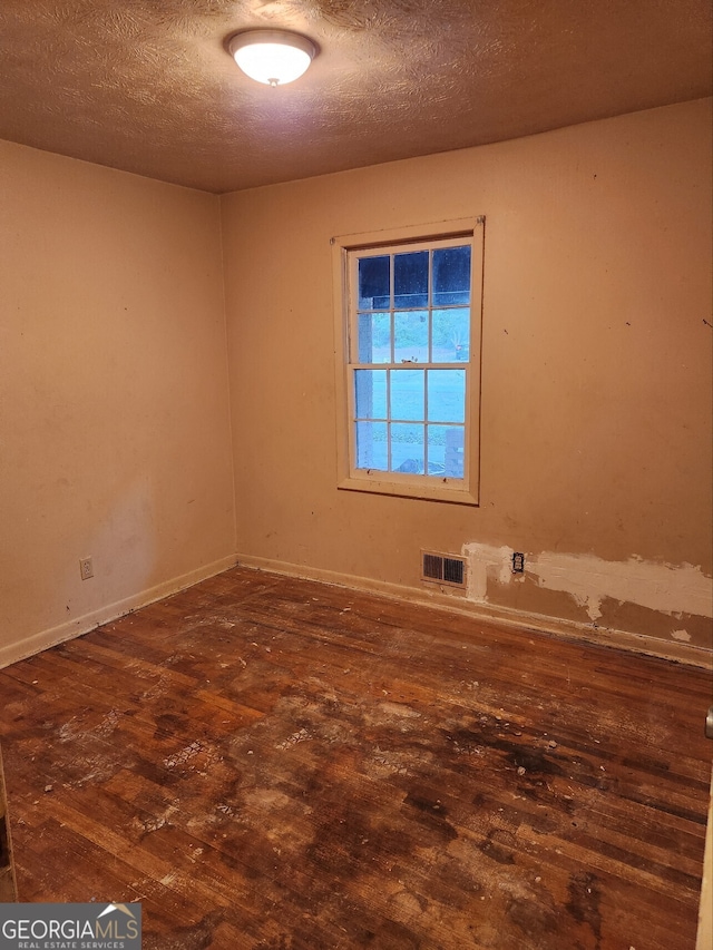 spare room with a textured ceiling and dark hardwood / wood-style floors