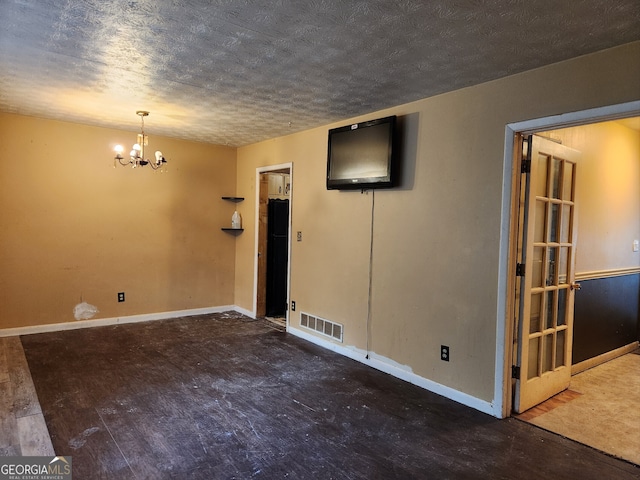 unfurnished room featuring wood-type flooring, a textured ceiling, and a notable chandelier