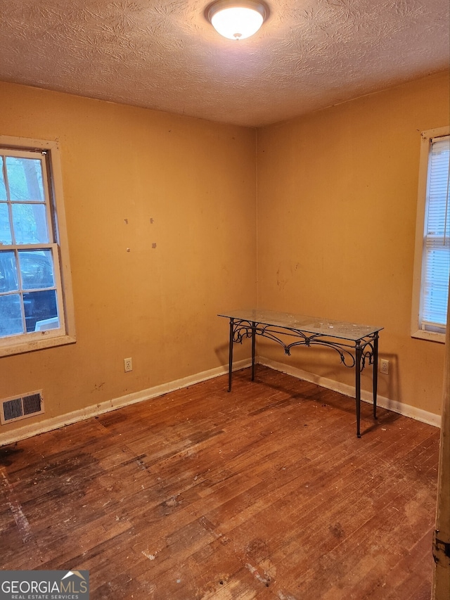 unfurnished room featuring hardwood / wood-style flooring and a textured ceiling