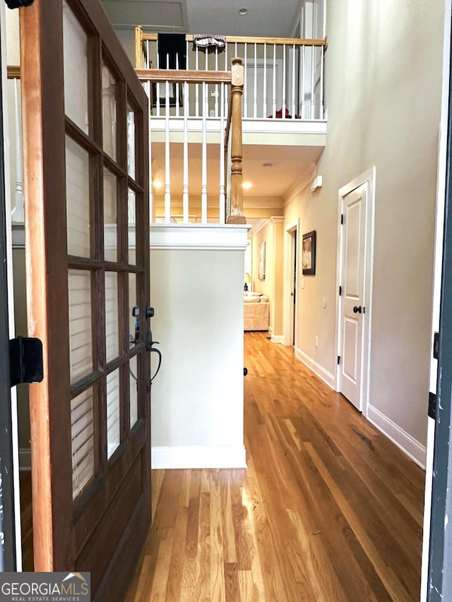 entrance foyer with a high ceiling, wood-type flooring, crown molding, and french doors