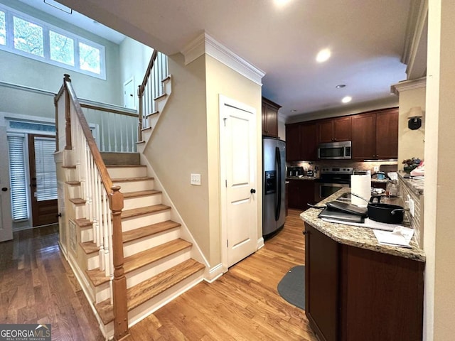 kitchen with dark brown cabinetry, light hardwood / wood-style floors, and stainless steel appliances