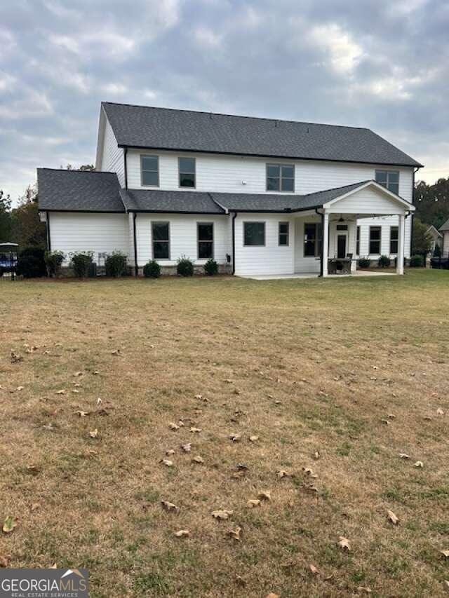 rear view of property featuring a lawn and a patio area