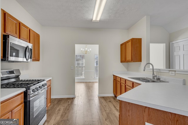 kitchen featuring light countertops, light wood-style flooring, appliances with stainless steel finishes, brown cabinetry, and a sink