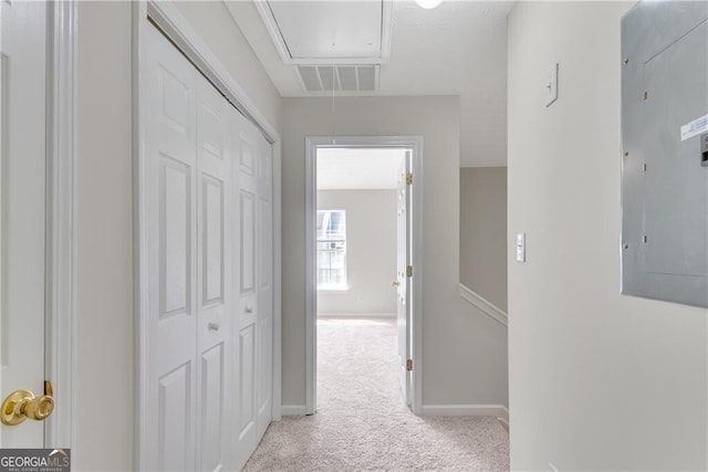 hallway featuring visible vents, baseboards, attic access, electric panel, and carpet flooring