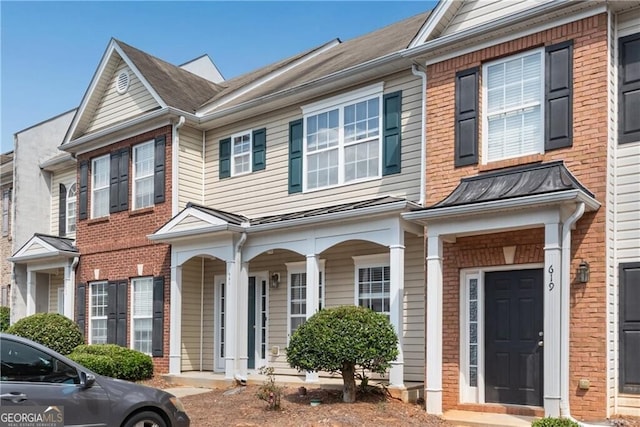 townhome / multi-family property with a standing seam roof and brick siding